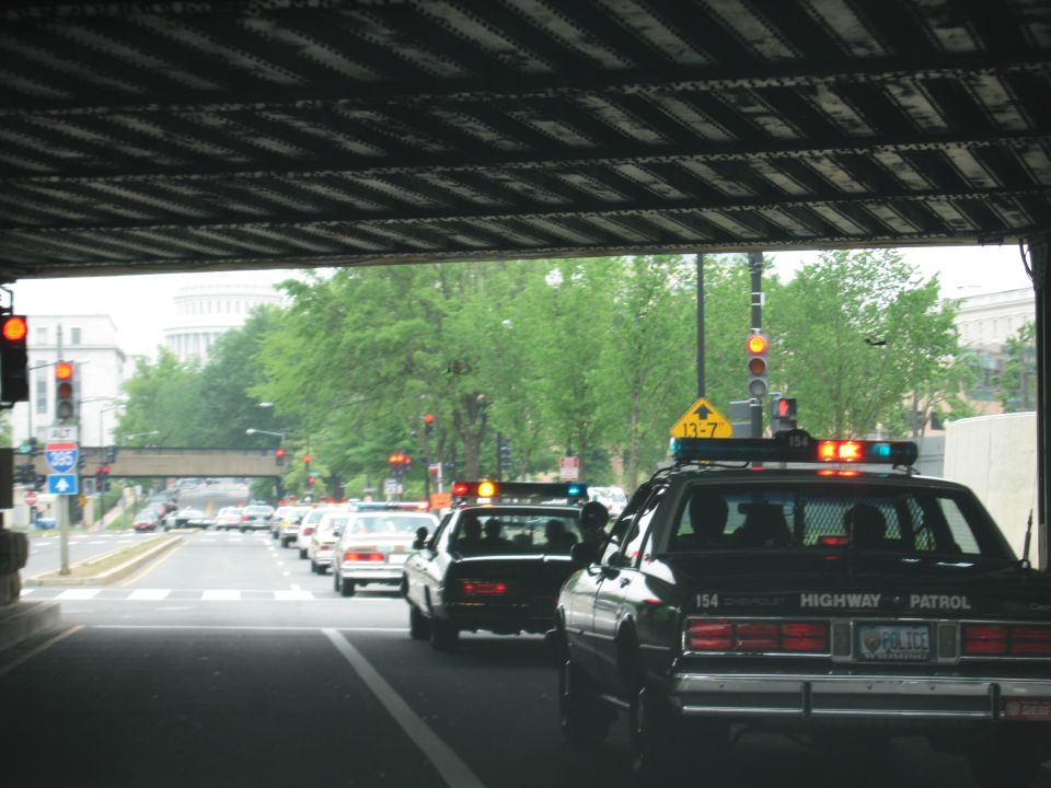 Line of police cars with flashing lights emerging from a tunnel underpass