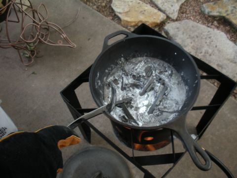 1996 Ford Bronco - Molten metal is being stirred in a pot over a burner, with a wire sculpture visible in the background.