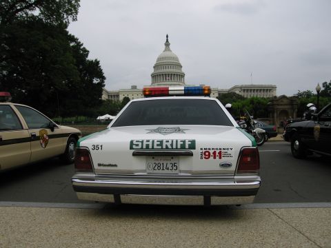 1991 Ford Crown Victoria - A police car with 'SHERIFF' text and emergency lights is parked in front of the Capitol Building.