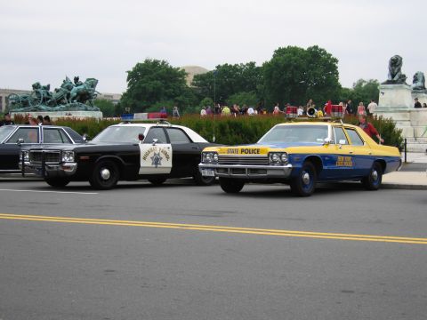 1991 Ford Crown Victoria - A 1977 New York State Police car is parked next to a black and white Highway Patrol vehicle.