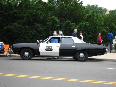 1991 Ford Crown Victoria - Side view of a vintage police car, likely from the 1970s, parked on a street.