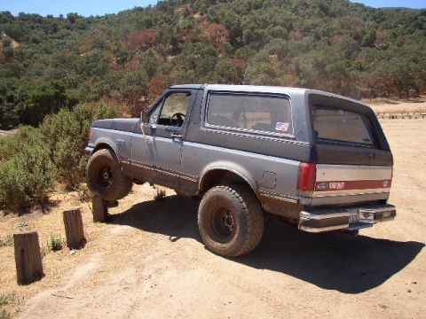 1989 Ford Bronco - Ford Bronco navigating an obstacle on a dirt trail during an off-road excursion.
