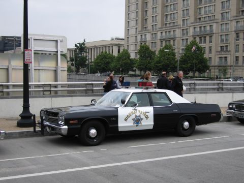 1991 Ford Crown Victoria - A vintage police car is parked on the street with people standing nearby.