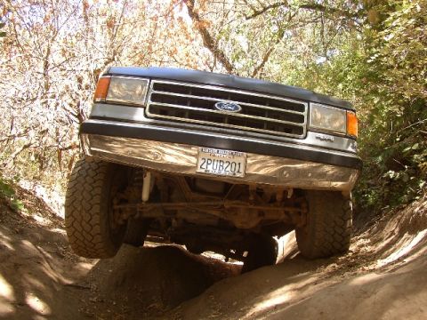 1989 Ford Bronco - This Ford Bronco is navigating a steep, off-road trail with one wheel elevated.