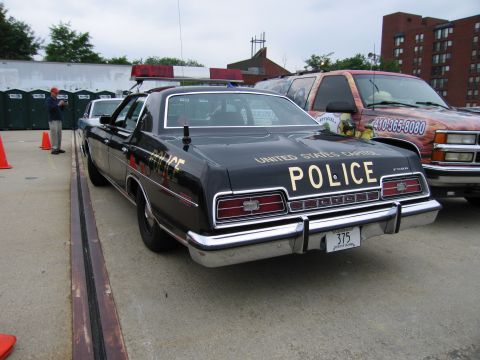 1991 Ford Crown Victoria - Rear view of a vintage police car, likely from the 1970s, with police markings and emergency lights.