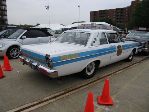 1991 Ford Crown Victoria - This vintage police car features a distinctive blue stripe and 'POLICE' lettering on its rear quarter panel.