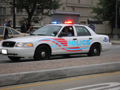 1991 Ford Crown Victoria - Side view of a police car with emergency lights active, showing "POLICE" text and unit number 8683.