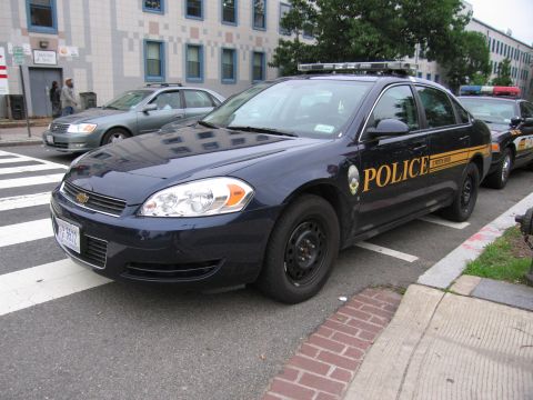 1991 Ford Crown Victoria - Two police cars are parked on a street next to a crosswalk and a building.