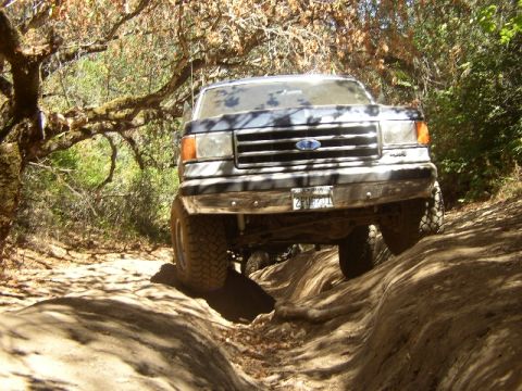 1989 Ford Bronco - This Ford truck, likely from the late 1980s, is shown tackling a challenging off-road path.