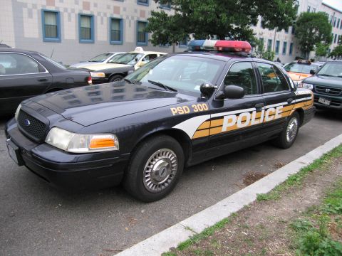 1991 Ford Crown Victoria - A dark blue police car with "POLICE" written on its side is parked on a street.