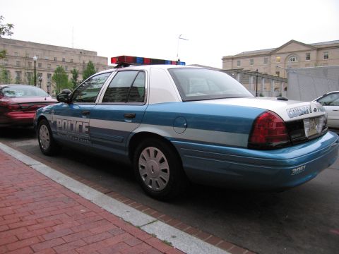 1991 Ford Crown Victoria - Side view of a police car with "COUNTY POLICE" text on the trunk, parked next to another vehicle.