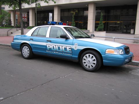1991 Ford Crown Victoria - Side view of a Prince William County police car parked on a street in front of a building.