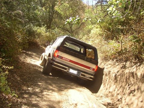 1989 Ford Bronco - Bronco navigating a challenging dirt path during an off-road excursion.