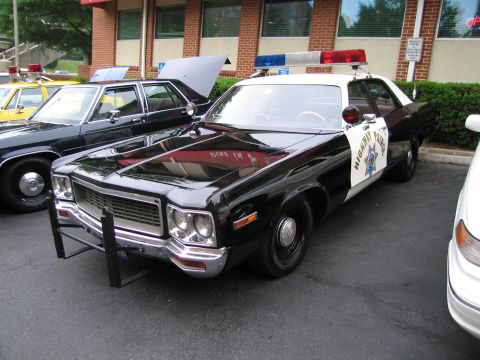 1991 Ford Crown Victoria - A black and white police car with a light bar is parked next to another vehicle.