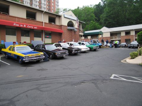 1991 Ford Crown Victoria - A collection of police vehicles are gathered in a parking lot outside a building.