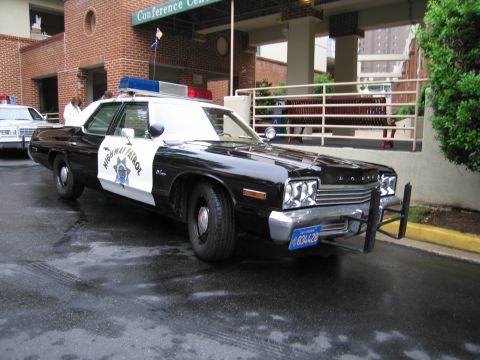 1991 Ford Crown Victoria - This 1977 Dodge Monaco police car is parked outside a building with a "Conference Center" sign.