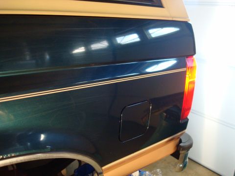 1995 Ford Bronco - Rear quarter panel detail of a dark green SUV with a tan top and pinstriping, consistent with a 1995 Ford Bronco.