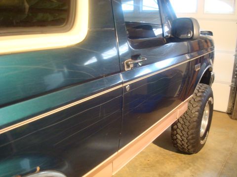 1995 Ford Bronco - Side view of a 1995 Ford Bronco showing extensive scratches on the dark green paint.