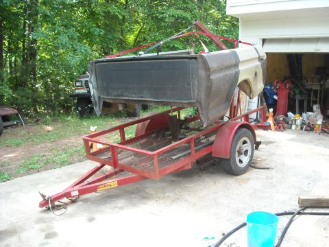 1979 Ford F-150 - The bed of a 1979 Ford F-150 is hoisted onto a trailer in front of a garage.