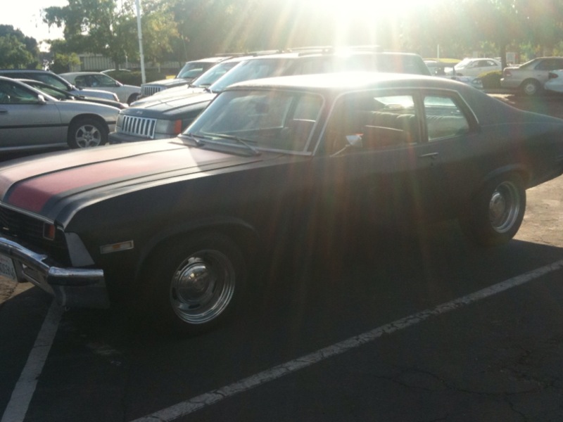 1973 Chevrolet Nova sedan parked in a lot, sun glare on windshield