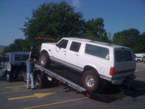 1996 Ford C-350 (Centurion Conversions) - A white four-door Ford crew-cab conversion SUV with an extended rear body, roof rack rails and chrome-modular wheels on knobby all-terrain…