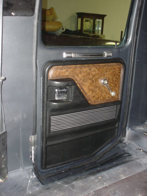 1979 Ford F-250 - Close-up view of the interior door panel, wood grain trim and a chrome window crank, consistent with a 1979 Ford F-250.