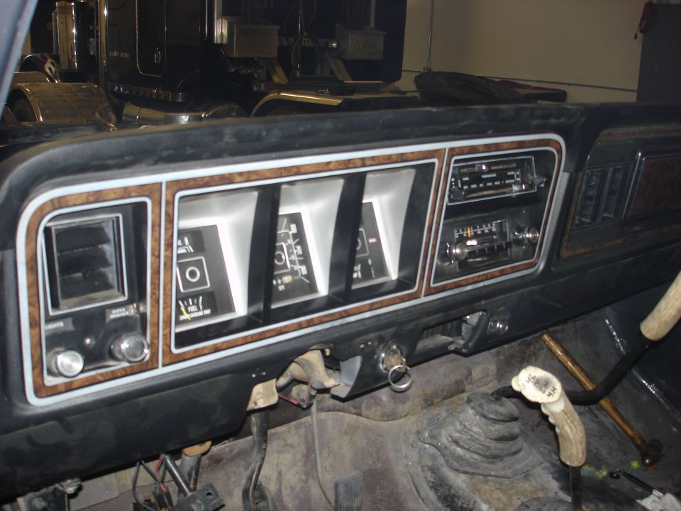 Dashboard with gauges, radio, and gear shifter. Wood grain trim is visible