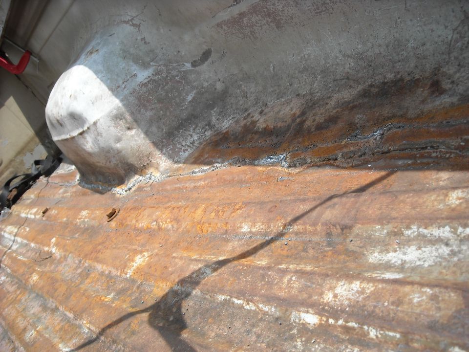 rusted corrugated metal panel with a rounded section and some weld marks