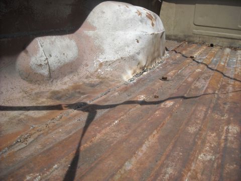 1979 Ford F-150 - The ribbed metal bed of a truck shows significant rust and wear, with a large, rounded hump covering the wheel well.