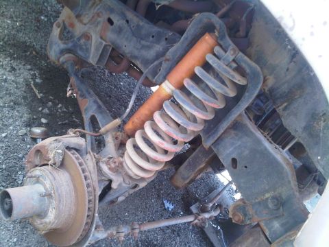 1986 Ford Bronco - Close-up of a vehicle's front suspension system, showing a coil spring and shock absorber.