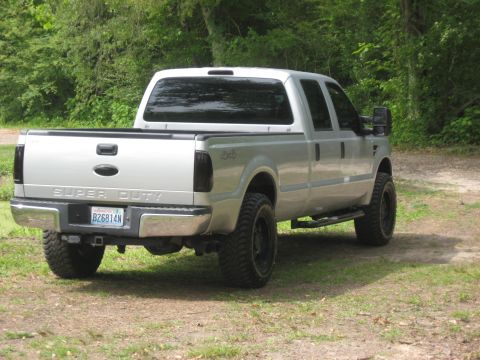 2008 Ford F-250 - A silver 2008 Ford F-250 Super Duty pickup truck is parked outdoors on a dirt and grass surface.