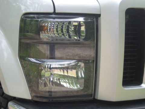 2008 Ford F-250 - Close-up of the front headlight assembly on a white 2008 Ford F-250 truck.