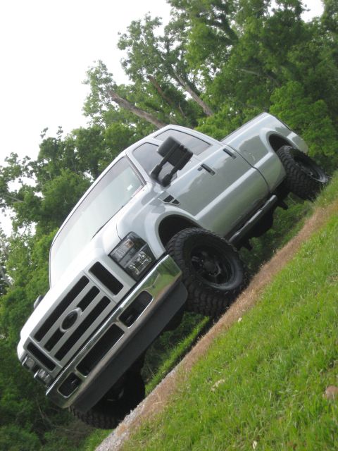 2008 Ford F-250 - This silver pickup truck, likely a 2008 Ford F-250, is shown from the front 3/4 angle with its large tires and black rims visible.