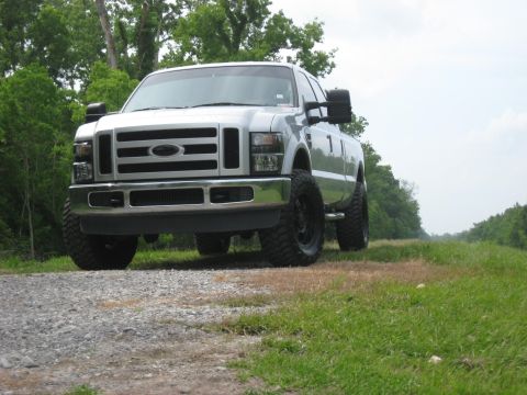 2008 Ford F-250 - A silver 2008 Ford F-250 pickup truck is parked on a gravel road with grassy areas on either side.