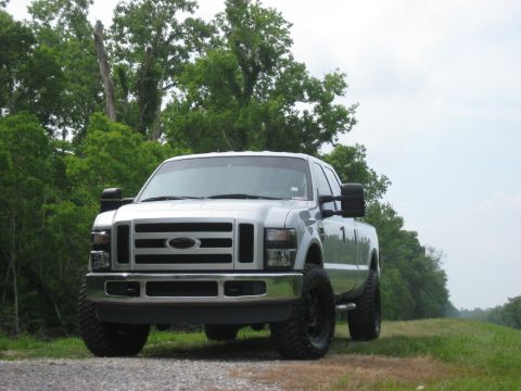 2008 Ford F-250 - A silver 2008 Ford F-250 pickup truck is parked on a gravel road with a line of trees in the background.