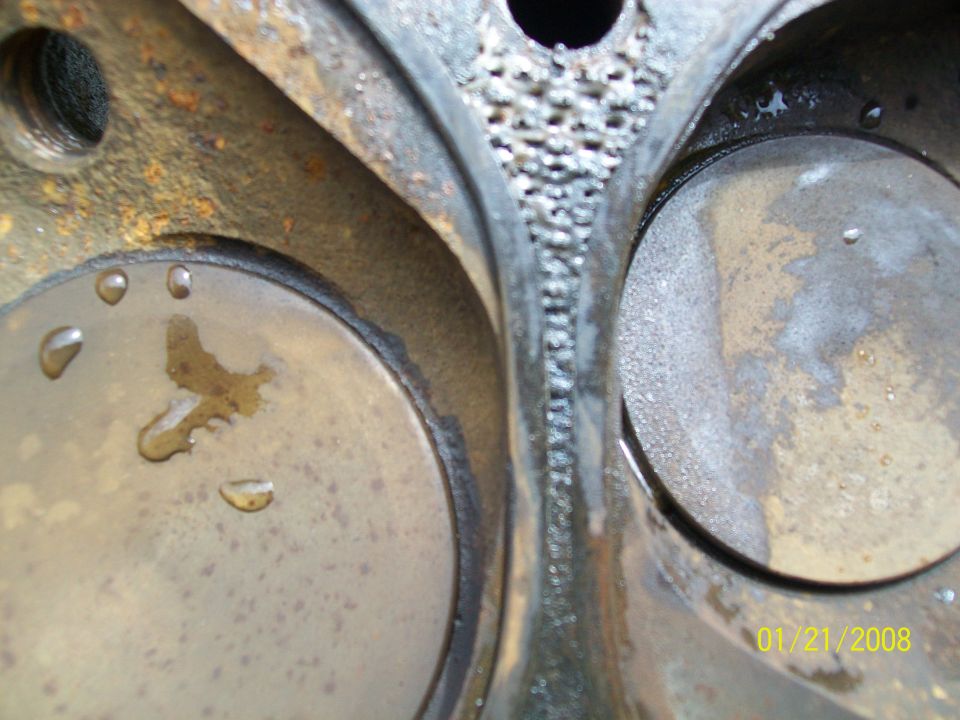 Engine cylinder head with two valves, showing rust and water droplets
