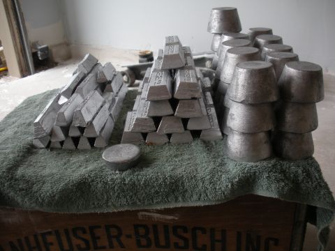 1996 Ford Bronco - Numerous metal ingots and cast parts are arranged on a towel, with a wooden crate visible below.
