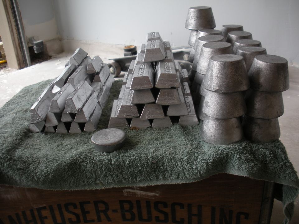 Stacks of metal ingots and cast parts on a towel over a wooden crate