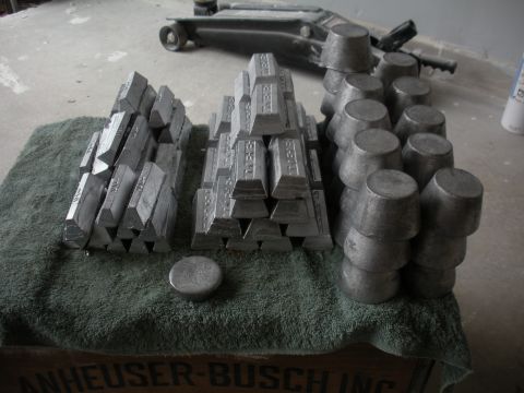 1996 Ford Bronco - Numerous metal ingots and castings are arranged on a towel, with a car jack visible behind them.
