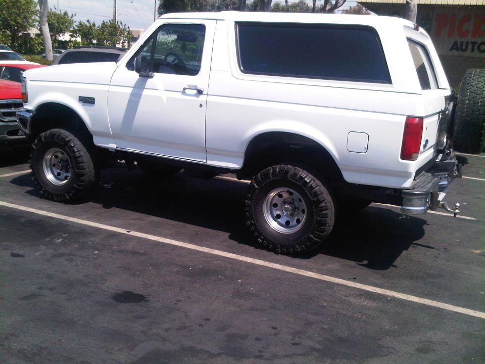 White Ford Bronco with lifted suspension and off-road tires parked in a lot