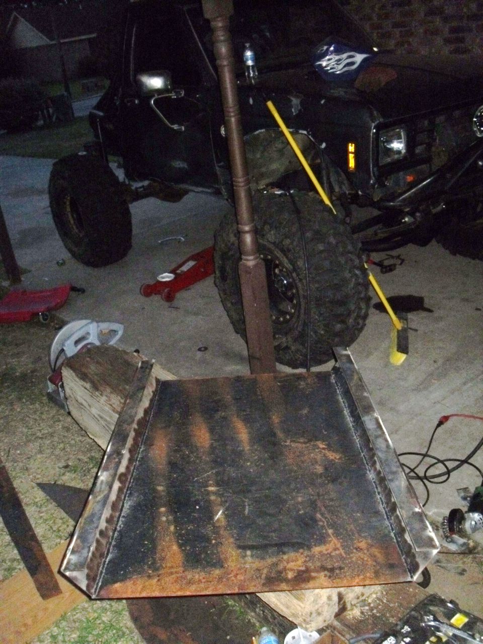 Black SUV with large tires and custom metal fabrication in foreground