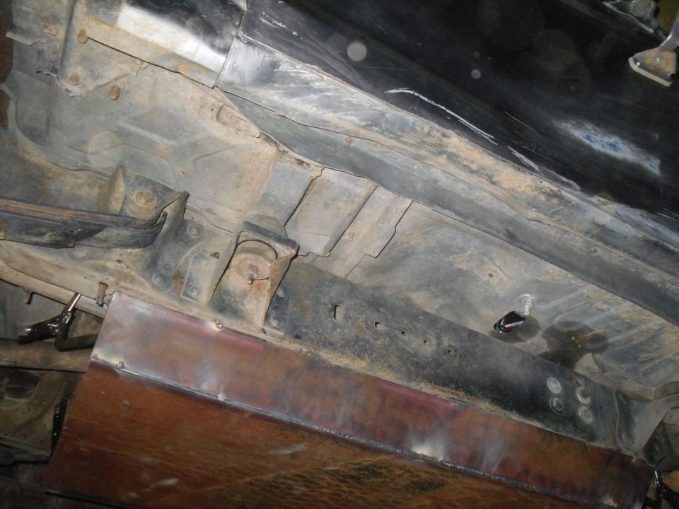 Vehicle underbody with rust and a newly welded metal plate on the side