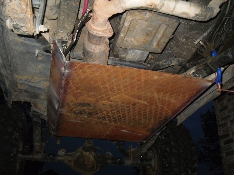 Underbody armor plate with diamond pattern, bolted to vehicle frame