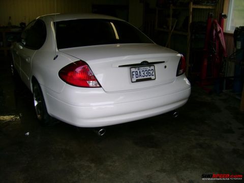 1993 Ford Taurus - The rear of a white sedan is shown in a garage setting, with its taillights and license plate clearly visible.
