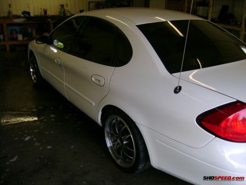 1993 Ford Taurus - White sedan with aftermarket wheels parked inside a garage.