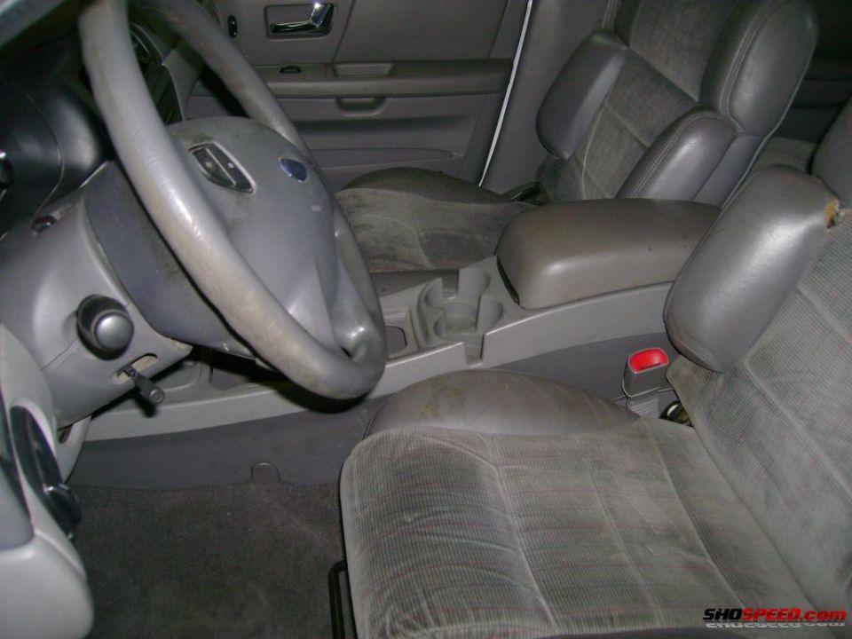 Gray fabric seats and dashboard of a car, with a Ford logo on the steering wheel
