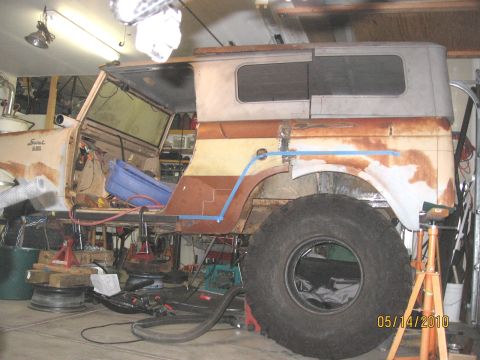 1961 International Scout 800 - A vintage International Scout body is in a workshop, showing signs of rust and modification work.