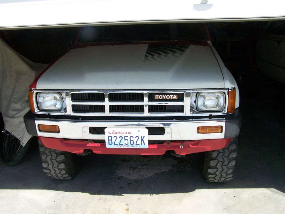 Toyota pickup truck front view, red bumper, gray hood with black stripes