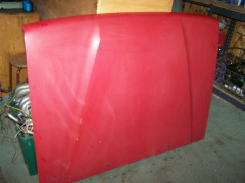 1988 Suzuki Samurai - A red vehicle hood is shown, detached from the vehicle, with some mechanical parts visible in the background.