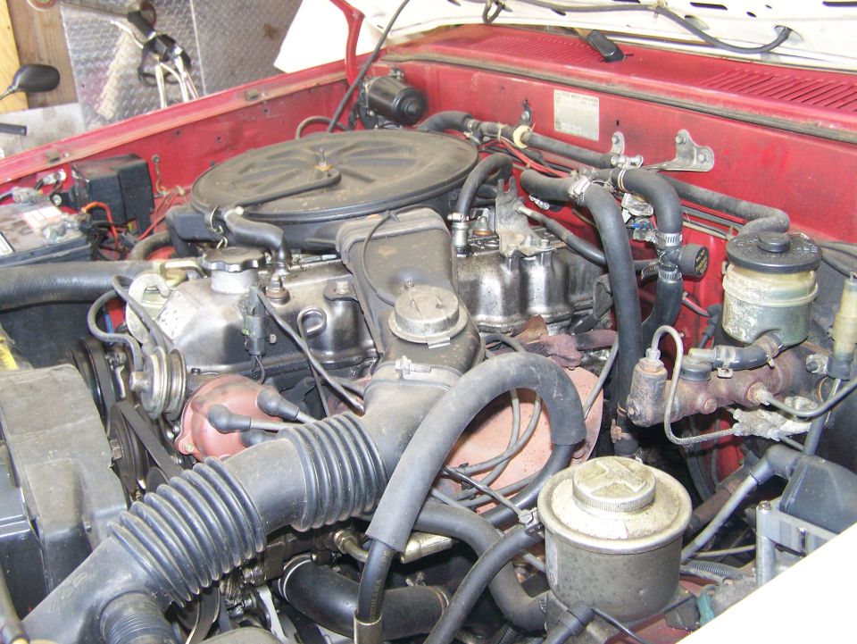 Engine bay with hoses, engine block, and air intake visible